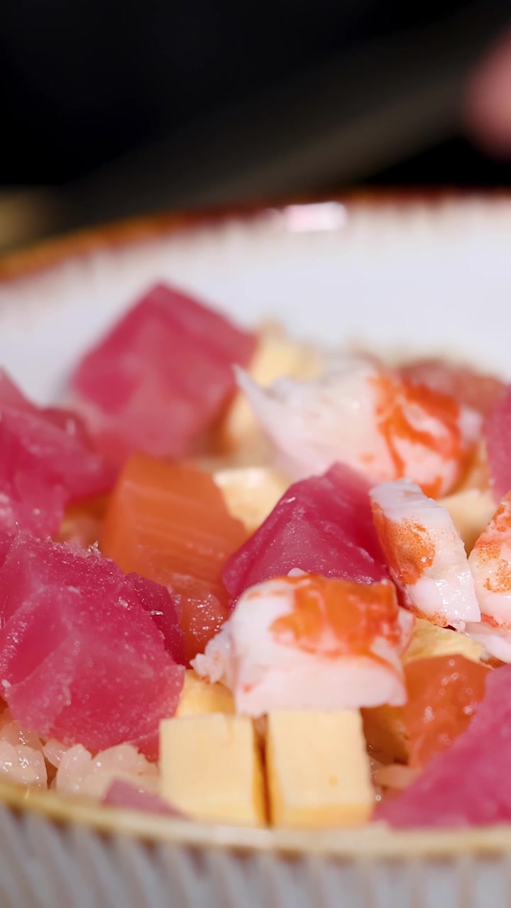 Primo piano delle mani di uno chef che dispongono con cura frutti di mare freschi sul riso in una ciotola