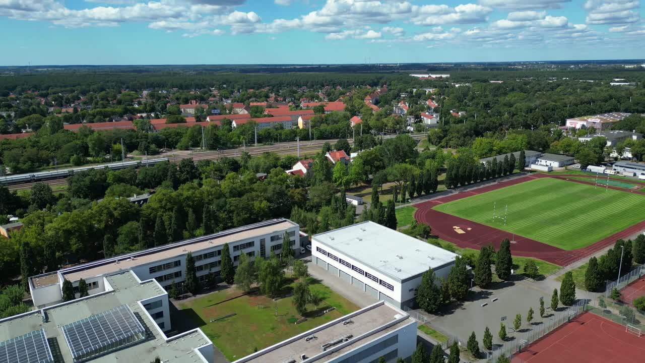 sports facilities at Hennigsdorf high school, including a soccer field, running track and other buildings in residential areas. Amazing aerial view flight fly push forward drone