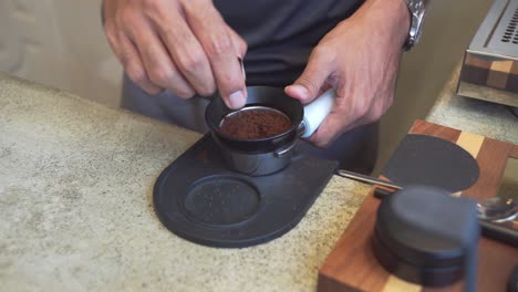 barista en la cafetería prepara granos de café recién molidos en un anillo de dosificación