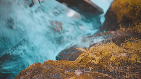 Rápidos-De-Agua-Que-Se-Precipitan-Chocando-Contra-Grandes-Rocas-En-El-Fondo-Con-Rocas-Cubiertas-De-Musgo-En-Primer-Plano-Durante-El-Otoño-4k-Prores