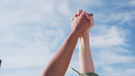 midsection of diverse female gay couple raising and holding hands