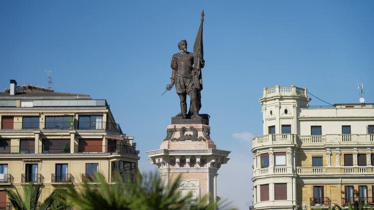 Statua dell'ammiraglio Antonio de Oquendo da un angolo inferiore, incorniciata da eleganti edifici classici di San Sebastian