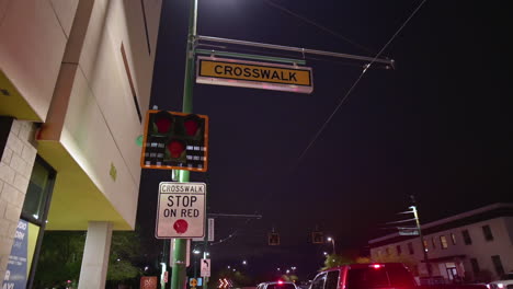 crosswalk sign, red trafic lights, and traffic warning in the city street at night