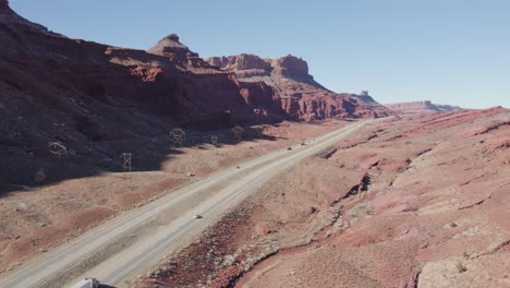 drone rising over highway with red rock mountains in back, moab utah