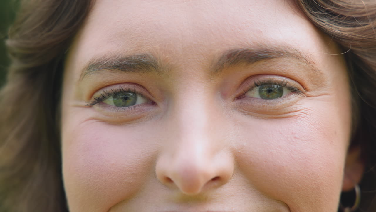 Smiling woman with bright eyes enjoying outdoor sunlight, feeling joyful and relaxed