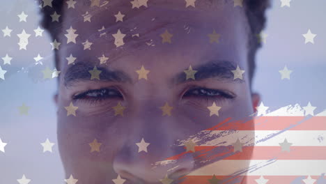 animation of american flag over portrait of happy biracial man opening eyes and smiling in sunshine