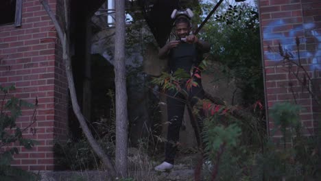 a black man with a gas mask on his head ignites a flare before placing the gas mask over his face in an abandoned red brick building