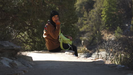 female tourist resting at walnut canyon applying lip balm