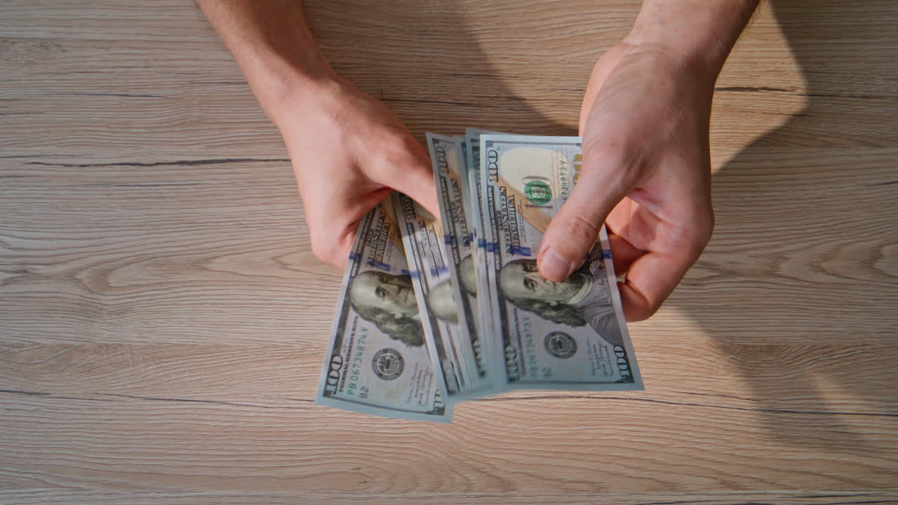 Man hands counting dollars at wooden table closeup top view. Unknown person cash