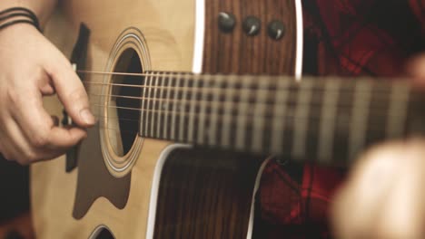 close up of a western acoustic guitars neck and strings while guitar chords are being played on it by a professional musician