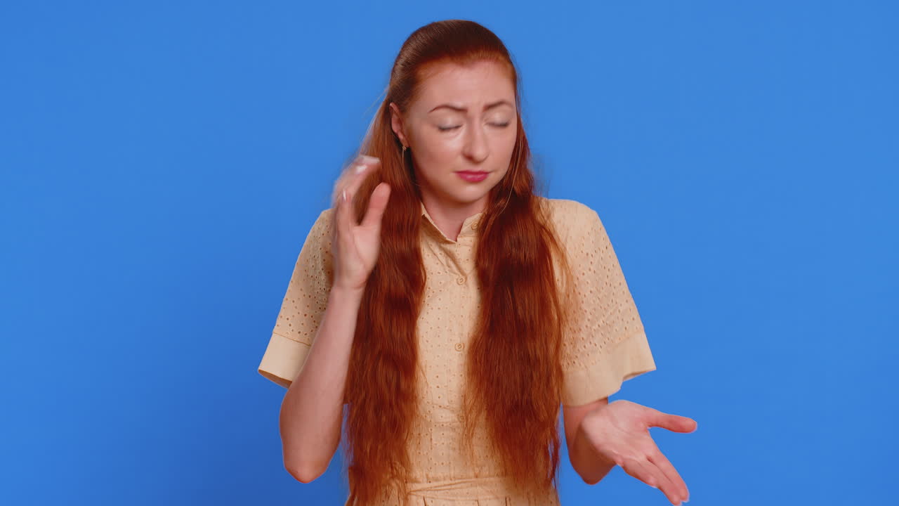 성인 여성은 당신을 듣기 위해 혼란스럽고 눈살을 푸리며, 더 큰 목소리를 위해 귀에 팔을 붙이고 있습니다.