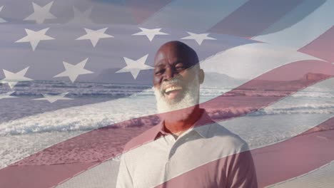 Animation-of-flag-of-united-states-of-america-over-happy-senior-african-american-man-on-beach