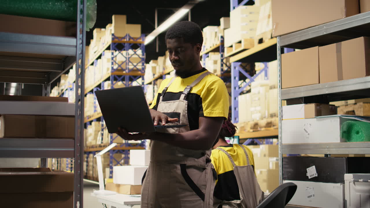 Young black employee sorting packages on shelves in a huge warehouse facility