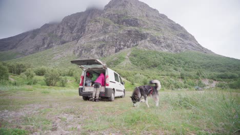 person with alaskan malamute and campervan near the mountain of donnamannen, norway