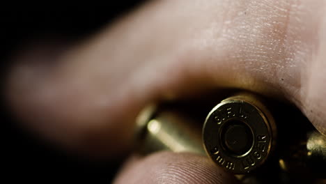 macro detail closeup of 9×19mm parabellum bullet held inside hand, rack focus