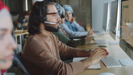 agente masculino de oriente medio con auriculares trabajando en el centro de apoyo