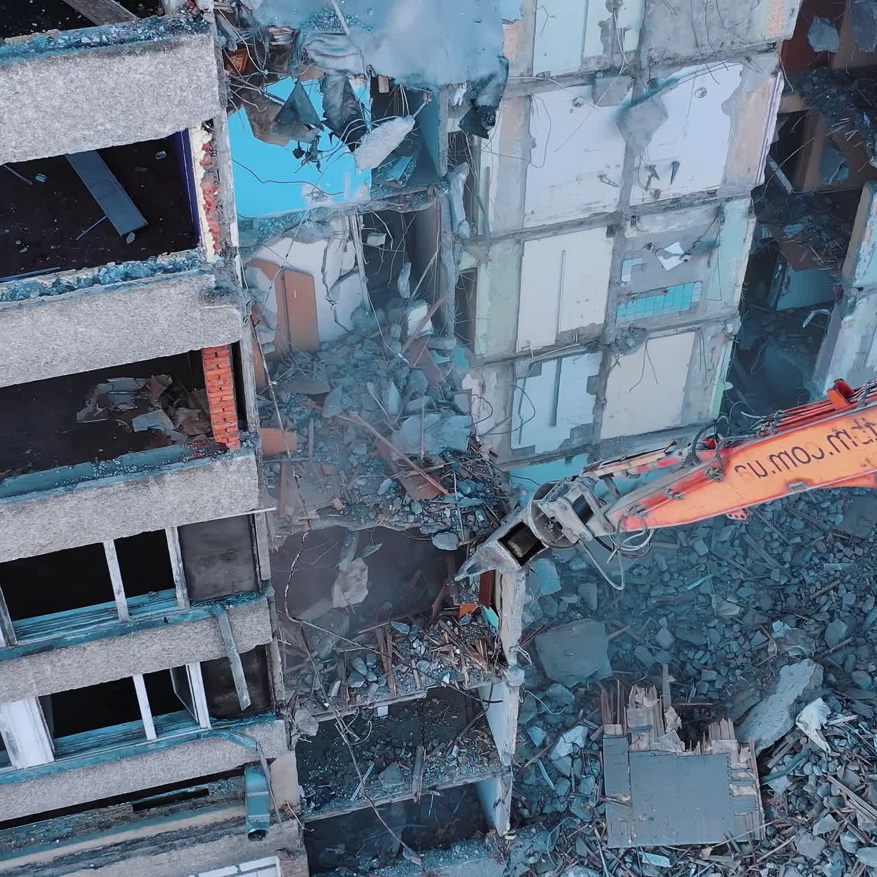 Excavator claw caught the piece of destructed house. Site of the ruins of old building. View from above