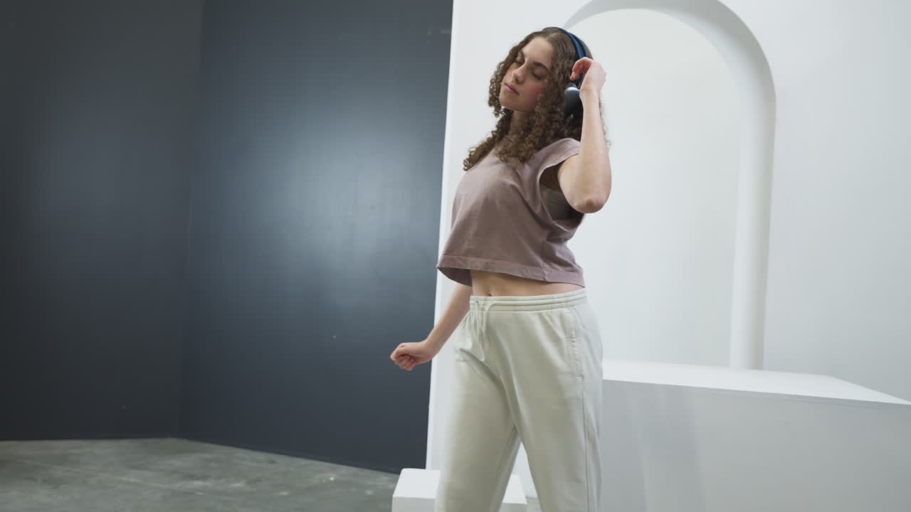 Crazy teenager enjoying herself while dancing with headphones. Slow motion