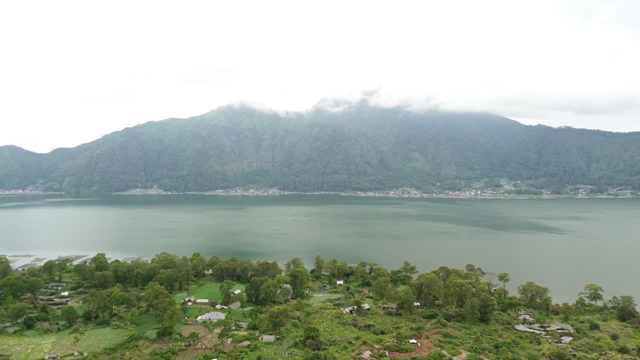 un tranquilo pueblo junto al lago rodeado de montañas y vegetación, vista aérea