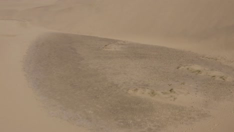 Drone-shot-of-dunes-in-a-desert-with-windy-sand