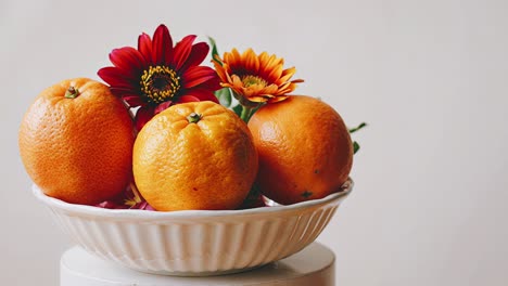 oranges and flowers in a white bowl