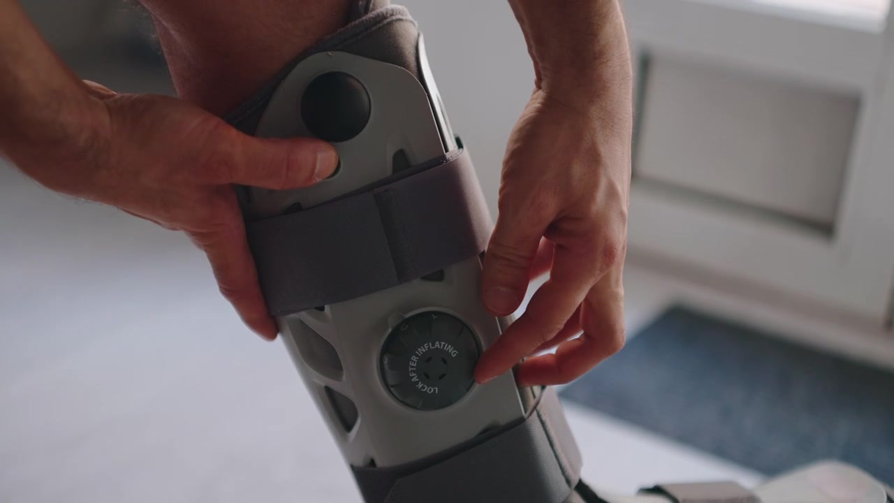 Man Adjusting Inflatable Medical Leg Brace for Recovery