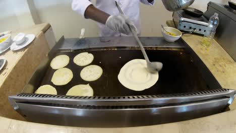cocinar haciendo chapati o pan plano indio, que es un desayuno o almuerzo vegetariano tradicional y popular, con curry de patata y cebolla y chutney de coco como platos secundarios.