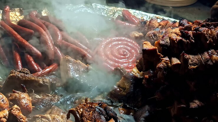 Asap dan api mengepul saat daging dimasak di dalam panci mendidih terbuka di halaman belakang Latvia.