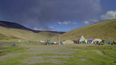 gente, excursionistas caminando alrededor de un campamento de tiendas de campaña en el himalaya, campamento base con un alto mástil de bandera de oración en nimaling