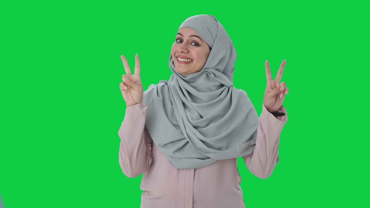 행복한 무슬림 사업가 여성이 승리의 표지판을 보여주는 녹색 화면