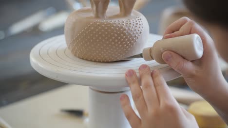 closeup of bottom of mug, which is being decorated in ceramic studio. female professional hands making clay dots or drops on the surface of vase by special squeezing tool