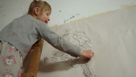 niña pintando en el papel en la pared