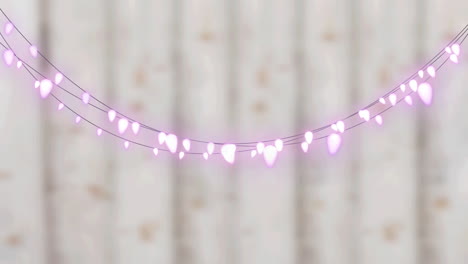 digital animation of pink decorative fairy lights hanging against wooden background