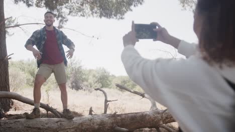 Happy-african-american-couple-using-smartphone-and-taking-pictures-in-forest,-slow-motion