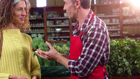 smiling male staff assisting a woman with grocery shopping