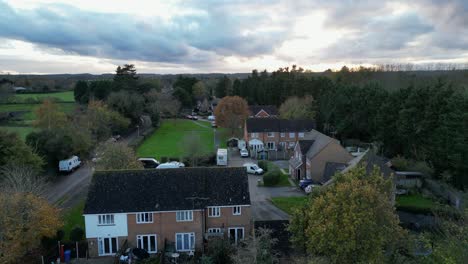 low-altitude drone shot of a suburban uk neighbourhood. houses, greenery, and vehicles are seen under a dramatic cloudy evening sky.