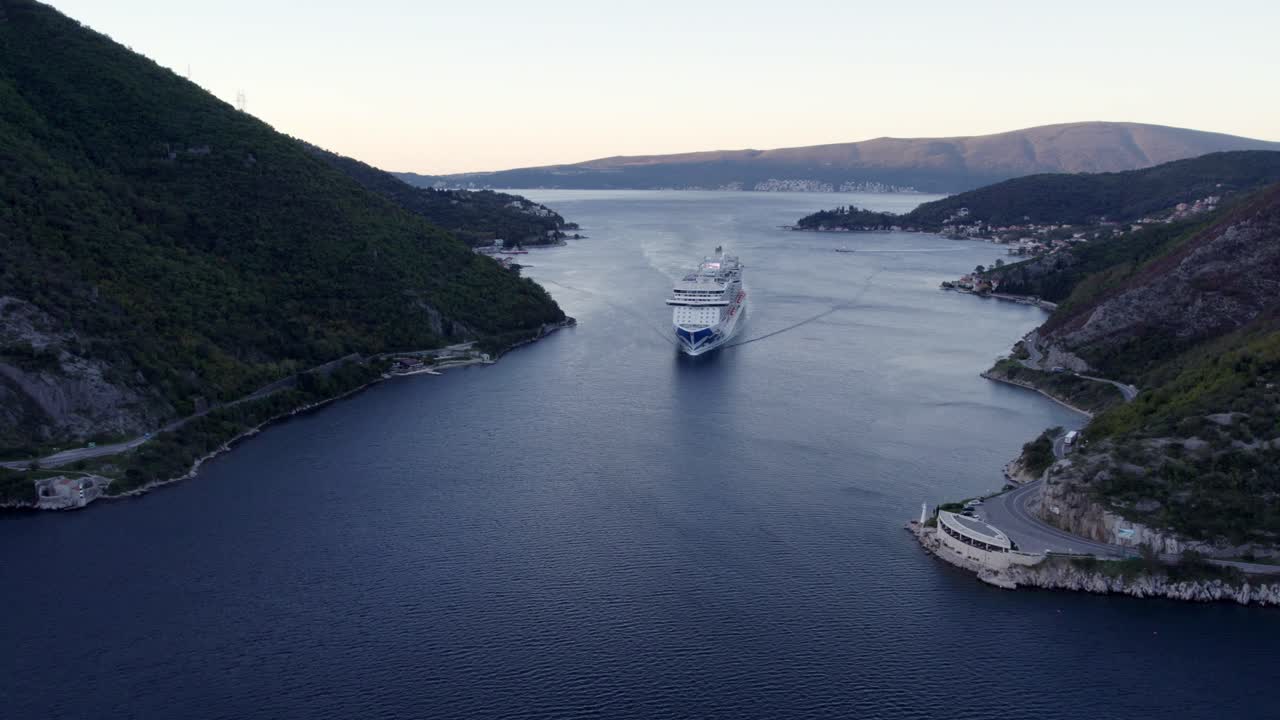 Luftfoto af krydstogtskib i den naturskønne Kotorbugt ved solopgang i Kotor, Montenegro med betagende solopgangsbelysning, rolig atmosfære, droneoptagelser i høj kvalitet der viser smukke landskaber.