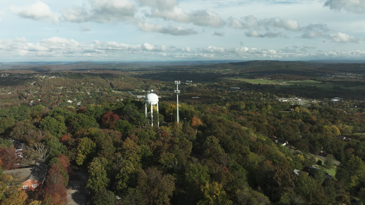 tanque de agua y torre de telecomunicaciones en medio de árboles de otoño en la montaña