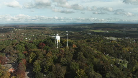 water tank and telecommunications tower amidst autumn trees on mountain