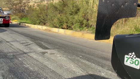 black race car slowly passing through before a race on the hill in malta - close up shot