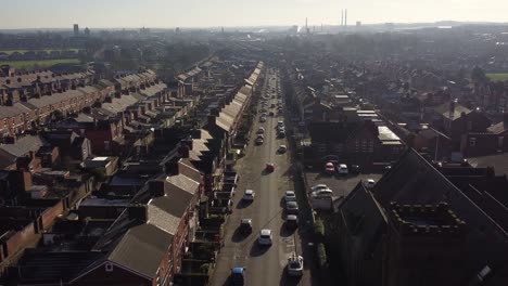 Aerial-rising-view-establishing-rows-of-Victorian-terraced-townhouse-community-with-a-long-road-leading-towards-town-centre-at-sunrise