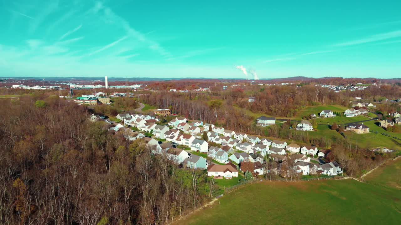 Drone establishing overview above residential suburb built in clearing between late fall trees