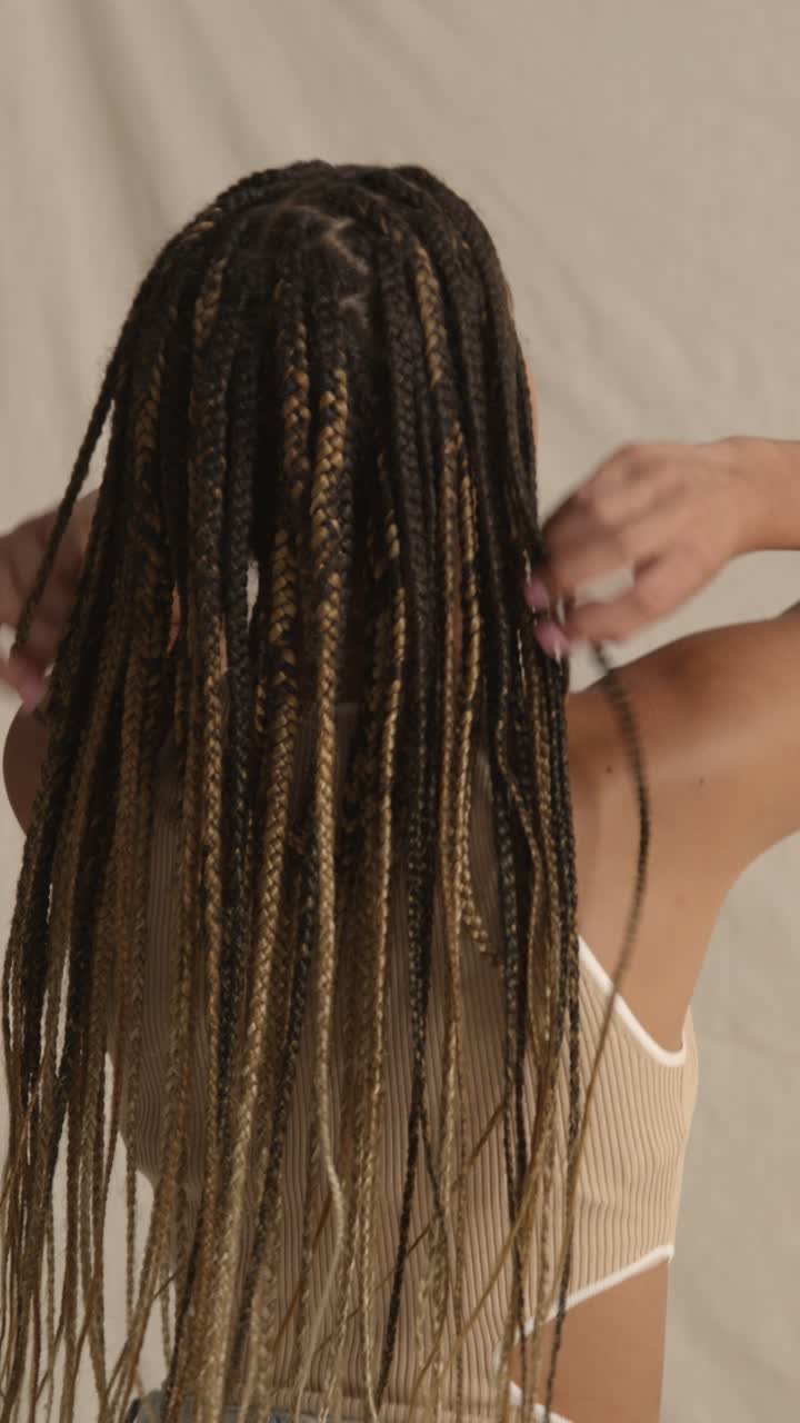 vista trasera foto de estudio de una mujer joven con cabello largo trenzado sintiendo suavidad después del producto de cuidado del cabello 1
