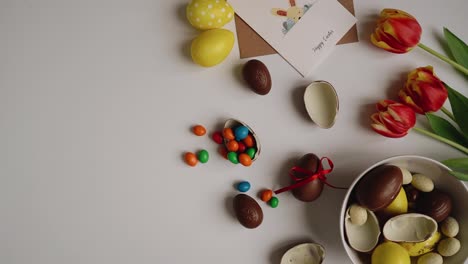 View-of-hands-putting-a-heap-of-small-painted-eggs-in-a-big-egg-shell-on-a-white-table