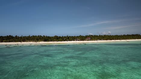 crystal clear turquoise waters and boats along the sandy shores of bantayan island, cebu philippines