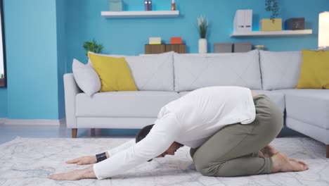 fitness instructor showing how to do balasana at home looking at camera.