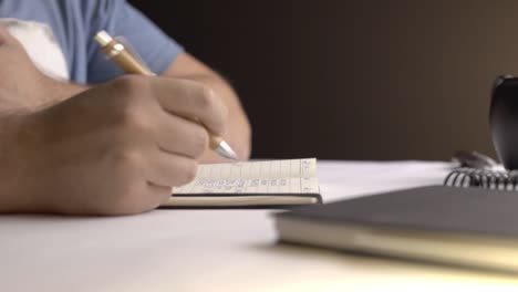 static shot of a man writing something in a small notebook