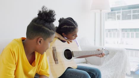 two african american teenagers learning to play a musical instrument or guitar