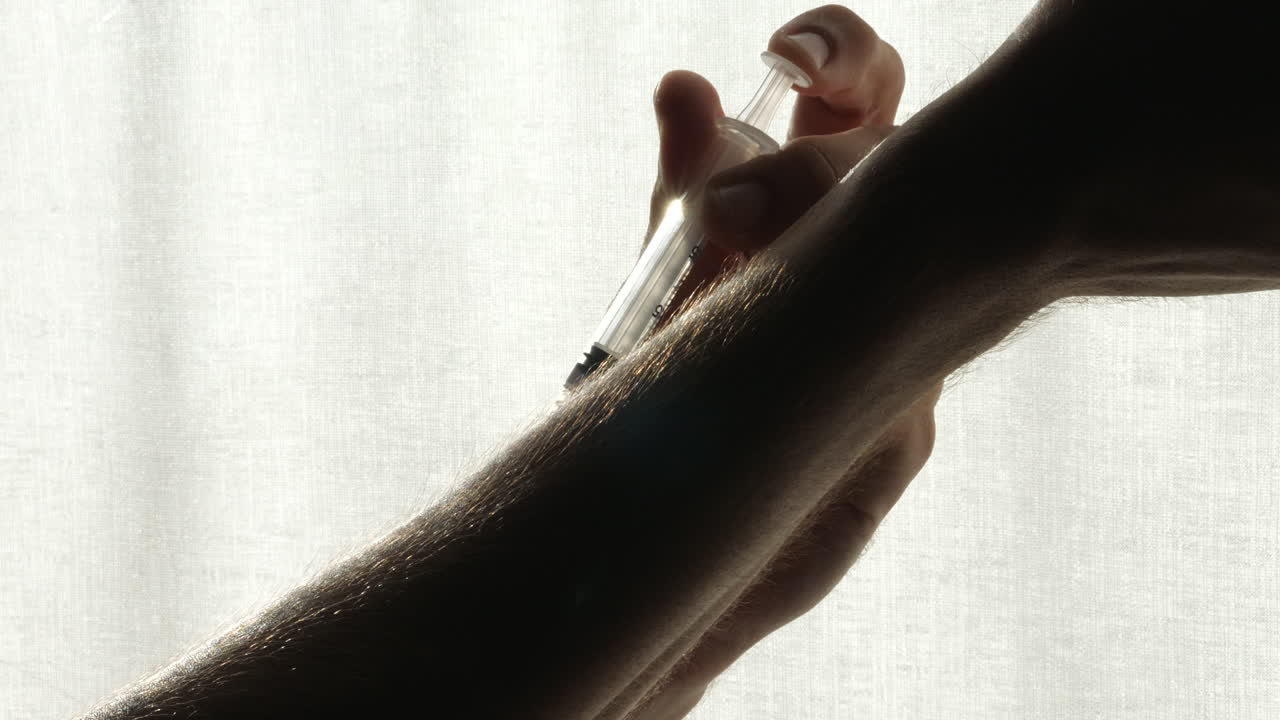 jeringa desechable con la droga en la mano masculina inyectándose en el brazo, inoculación - aislada en fondo blanco con camino de recorte