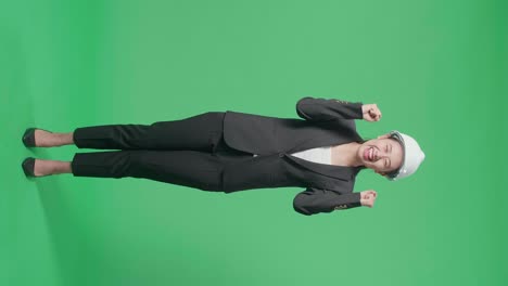 full body of happy asian female engineer with safety helmet celebrating while standing on green screen in the studio